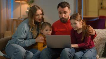 Family mother father children Caucasian parents kids little girls daughters on home couch evening weekend using laptop online shopping watch movie computer addict play game lose fail upset sad photo
