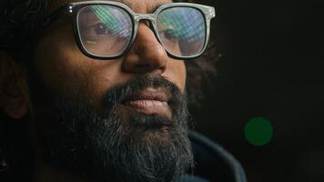 Thoughtful serious Indian businessman in eyeglasses looking away lost in thoughts thinking. Close up focused pensive bearded Arabian man with lights green reflection in glasses. Business vision idea photo