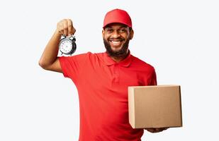 On-Time Courier Service. Delivery Guy Holding Clock And Cardboard Box Standing In Studio Over Yellow Background. photo