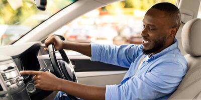 Road Playlist. Side View Profile Portrait Of Happy Black Man Driving Car And Listening To Music On Auto Audio System, Checking Automobile Options During Test Drive Pushing Button On Turning On Radio photo