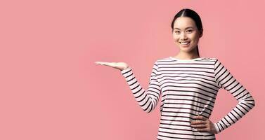 Check This. Positive Asian Woman Holding Something On Her Open Empty Palm, Smiling Korean Female Demonstrating Invisible Object, Standing Isolated Over Pink Background, Panorama With Copy Space photo