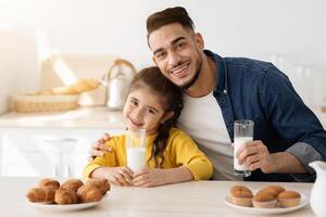 Cute Little Arab Girl Having Snacks With Daddy In Kitchen, Enjoying Homemade Pastry And Drinking Milk, Happy Middle Eastern Family Having A Bite With Croissants And Muffins At Home, Free Space photo