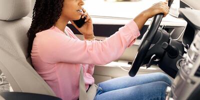 Portait of serious African American woman talking on mobile phone while driving car, unwary female driver using her cellphone, profile side view of unhappy lady arguing and riding in the city photo