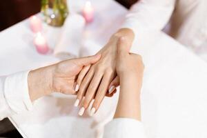 Two women enjoy a pampering manicure session at a salon, focusing on nail care. Candles create a calming atmosphere while hands are gently massaged and manicured. photo