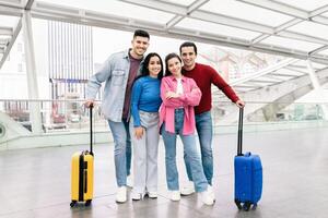 A happy couple stands with two friends in an airport terminal, ready for their weekend getaway. Bright smiles and colorful luggage show their excitement for travel and adventure. photo