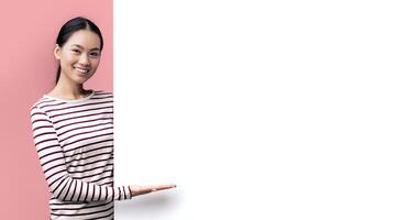 Beautiful Young Smiling Asian Lady Pointing At Big White Advertisement Board With Open Palm, Positive Korean Female Showing Free Copy Space On Blank Billboard, Posing Over Pink Studio Background photo
