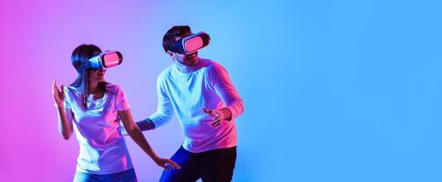 Millennial guy and lady in virtual reality glasses in neon, copy space photo