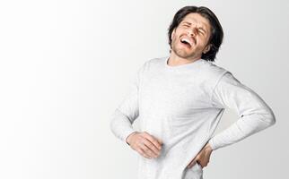 Sharp back pain. Man suffering from pain and screams, isolated on gray background, studio shot, panorama photo