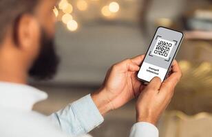 QR code on mobile phone screen, closeup. Unrecognizable african american man holding modern smartphone with bar code, paying for goods and services with payment system, creative image photo