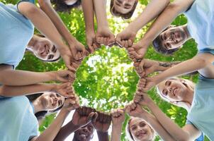 Happy volunteers fist bump together, standing in park and making circle, unity and collaboration concept, copy space photo