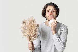 Allergy concept. Funny shocked man with red nose, napkin and bouquet photo