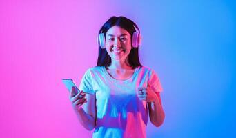 Asian lady with headphones and smartphone in hand, showing sign like photo