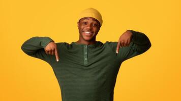 Look At This. Excited Black Guy Pointing Down With Two Hands, Cheerful African American Man Demonstrating Free Copy Space For Your Design And Advertisement While Posing Over Yellow Background photo