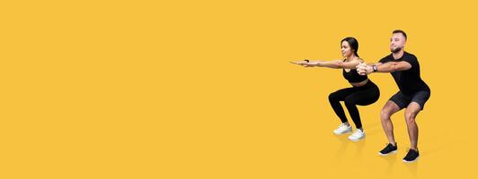 Two individuals are engaged in synchronized squats, showcasing proper form and teamwork. The bright yellow background enhances their focused expressions, creating an energetic atmosphere. photo