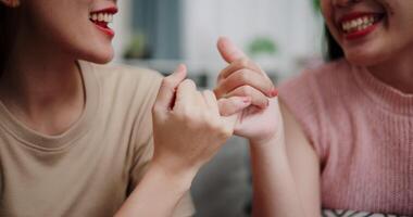 Handheld selective focus shot, Asian female couple share good feelings for each other and hold hands with their pinky fingers, indicating a good relationship or sincere promise, Happy times at home video