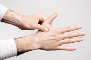 Arthritis and finger pain. Man presses to sore spot, close up, isolated on gray background, studio shot photo