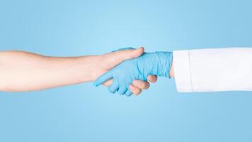 Closeup view of man shaking hands with doctor in rubber glove on white background photo
