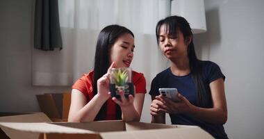 Handheld shot, Two siblings happily chatting on the floor and using mobile phone to check if the items in the boxes they moved from old house are complete. Moving to a new home concept video