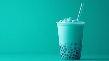 A vibrant teal bubble tea filled with chewy tapioca pearls is served in a clear cup. A straw is inserted, and the drink is set against a solid turquoise backdrop, creating an inviting look. photo