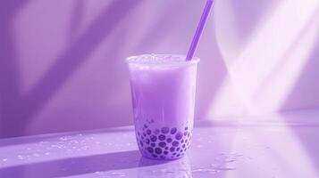 A clear cup filled with colorful purple bubble tea rests on a shiny surface, showcasing round tapioca pearls at the bottom. photo