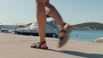 Female tourist strolling along pier with boats in background. video