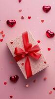 Colorful gift box adorned with red ribbon and hearts on pink background for special occasions photo