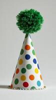 Colorful party hat with polka dots and pom pom displayed on a plain background photo