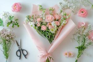 Arrangement of pink flowers and crafting materials on table for floral project photo