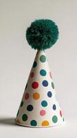 Colorful party hat with polka dots and pom pom displayed on a plain background photo