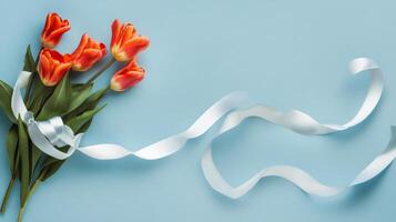 Beautiful bouquet of tulips and babys breath on soft blue background with ribbon photo