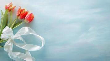 Beautiful bouquet of tulips and babys breath on soft blue background with ribbon photo