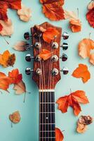 Acoustic guitar with autumn leaves arranged on a light blue background photo