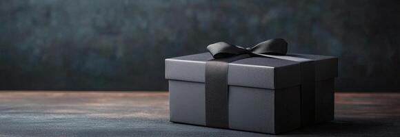 Elegant black gift box with ribbon on dark textured surface ready for special occasion photo