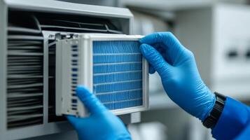 A person in blue gloves holding a filter in front of a machine photo