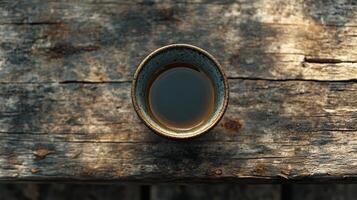 A cup of tea sits on top of a wooden table photo
