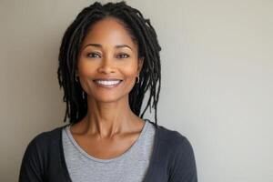 Portrait of a woman with long dreadlocks smiling against a light background photo