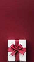 Elegant gift box with red ribbon on a rich maroon background for special occasions photo