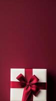 Elegant gift box with red ribbon on a rich maroon background for special occasions photo
