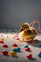 A cute duckling stands on a colorful surface surrounded by candies and a candy cane. photo