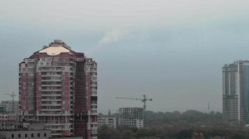 Cityscape with pipe smoke timelapse. Fog weather clouds and smoke from old brick smokestack. Residential buildings and construction crane silhouettes. Environment pollution and climate change concept video