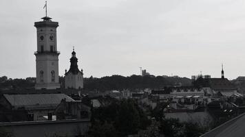 Monochrome retro filter time lapse of ancient Town Hall and house rooftops of old town in Europe. Architecture in Viennese Classical style. Lviv town hall clock tower at Market Square aerial view video