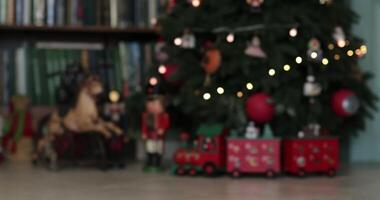 Advent calendar in shape of wooden train under faux Christmas tree decorated with retro Christmas ornaments. Antique nutcracker soldier toys and horse under faux fir tree. Moving from blur into focus video