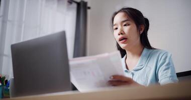 Handheld low angle view shot, Female freelancer holding document explaining project in online meeting with team members via laptop in home office. Working from home, Remote working. video