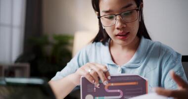 Footage of handheld, Female freelancer holding document explaining project in online meeting with team members via laptop in home office. Working from home, Remote working. video