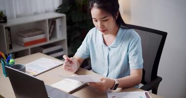 Handheld high angle view shot, Female freelancer holding document explaining project in online meeting with team members via laptop in home office. Working from home, Remote working. video