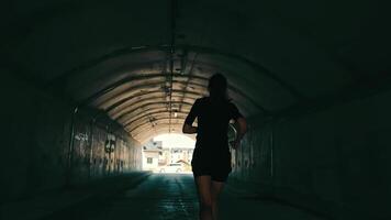 Woman running in a tunnel towards the light. Athlete runs in the tunnel. Active lifestyle. video
