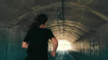 woman running in a dark tunnel to meet the light. Silhouette of a woman from behind running to the light. video