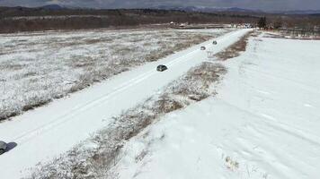 View from a drone on a winter road in a field along which cars drive. video