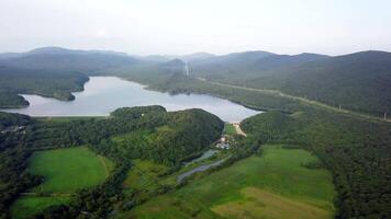 Drone view of smooth water and a dam surrounded by green hills video