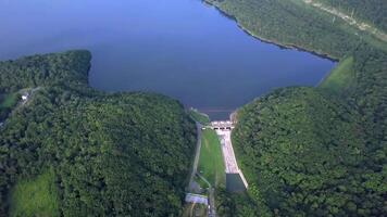 Drone view of smooth water and a dam surrounded by green hills video